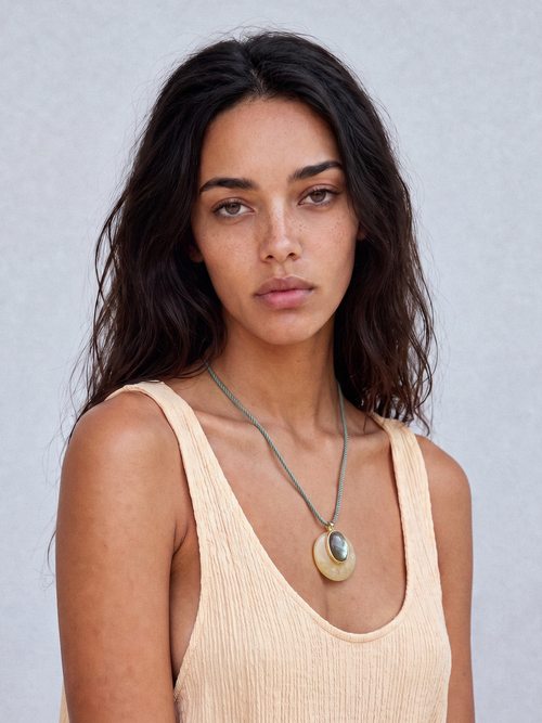 Model wearing the MOUNSER Aarnio Pendant in Olive Oil with yellow jade and labradorite disc pendant on twisted cord.