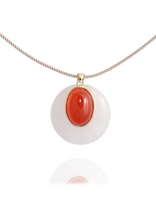 Close-up detail of the MOUNSER Aarnio Pendant in Petal showing the domed white quartz disc, oval red carnelian cabochon, and 14k gold-plated brass setting on beige twisted cord with reflection.
