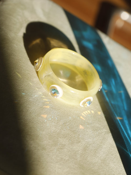 Close-up of the MOUNSER Ambrosia Bangle highlighting vivid Austrian crystals set into polished butter yellow resin.