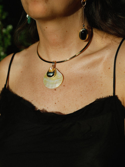 Close-up of the MOUNSER Half Shell Necklace worn on the collarbone, showing the mother-of-pearl shell pendant and freshwater pearl accent in detail
