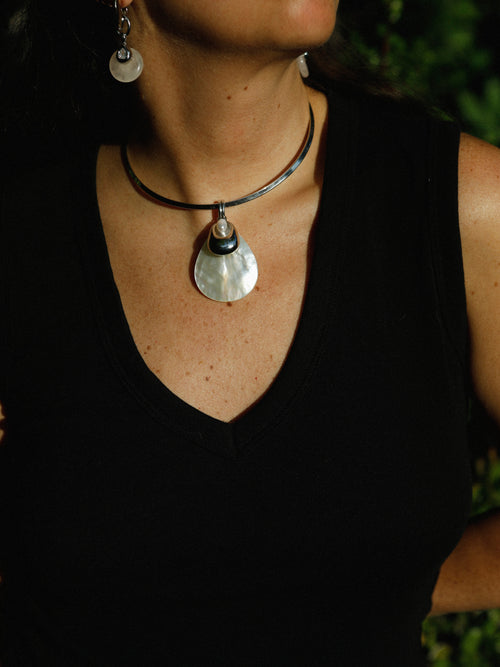 Close-up of the MOUNSER Half Shell Necklace worn on the collarbone, showing the mother-of-pearl shell pendant with sculptural detail and freshwater pearl accent in detail