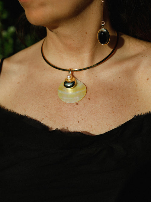Woman wearing the MOUNSER Half Shell Necklace, a sculptural mother-of-pearl pendant with freshwater pearl and gold accent on a fixed collar, from the Seascape Abstracted Collection
