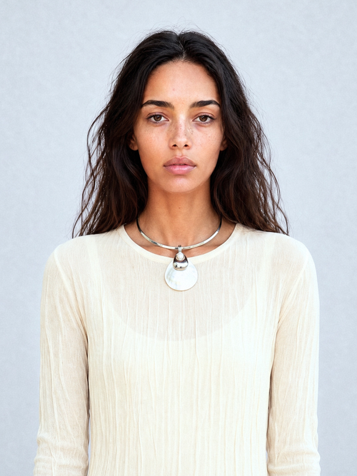 Model wearing the MOUNSER Half Shell Necklace, a sculptural shell pendant with freshwater pearl and silver accent on a fixed silver collar, from the Seascape Abstracted Collection