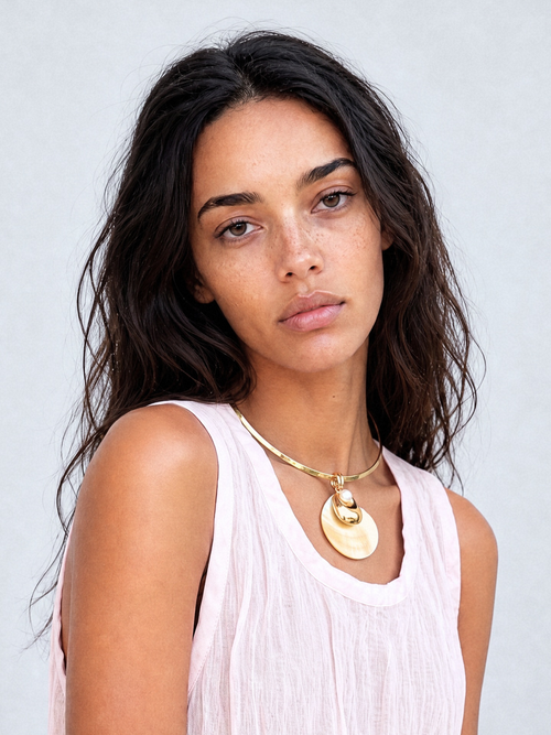 Model wearing the MOUNSER Half Shell Necklace, a sculptural mother-of-pearl free form pendant with freshwater pearl and gold accent on a fixed wire collar, from the Seascape Abstracted Collection