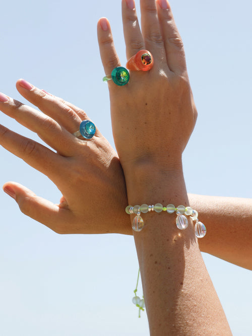 Outdoor shot of MOUNSER Bliss Ring in Tarocco a delicate and minimal acrylic cocktail ring in a jewel toned palette with a Swarovski crystal gemstone.  