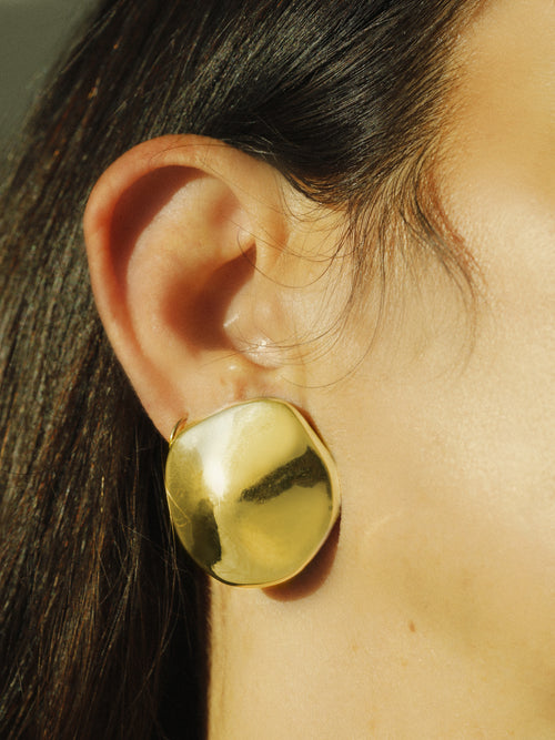 close up shot of MOUNSER Cookie Earrings in Gold fluid disc shaped sculptural stud earring