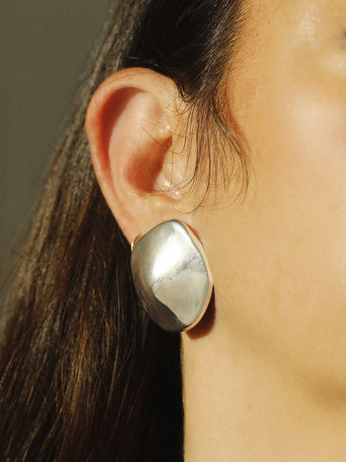 detail shot of MOUNSER Cookie Earrings in Silver fluid disc shaped sculptural stud earring