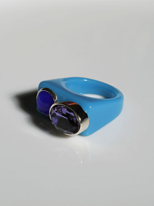 Angle view of MOUNSER Couplet Ring in Hydrangea a jewel toned dual stone ring featuring a Swarovski rhinestone and natural gemstone cabochon on a lucite band