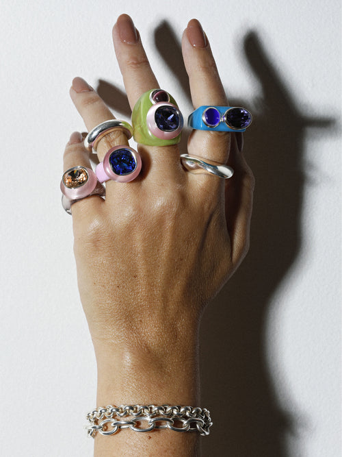 On hand view of MOUNSER Couplet Ring in Hydrangea a jewel toned dual stone ring featuring a Swarovski rhinestone and natural gemstone cabochon on a lucite band