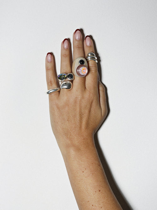 On hand view of MOUNSER Couplet Ring in On Ice a jewel toned dual stone ring featuring a Swarovski rhinestone and natural gemstone cabochon on a lucite band