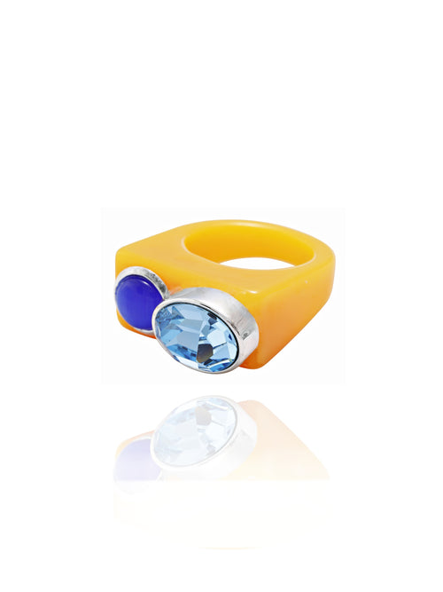 Angle view of MOUNSER Couplet Ring in Sunscreen a jewel toned dual stone ring featuring a Swarovski rhinestone and natural gemstone cabochon on a lucite band