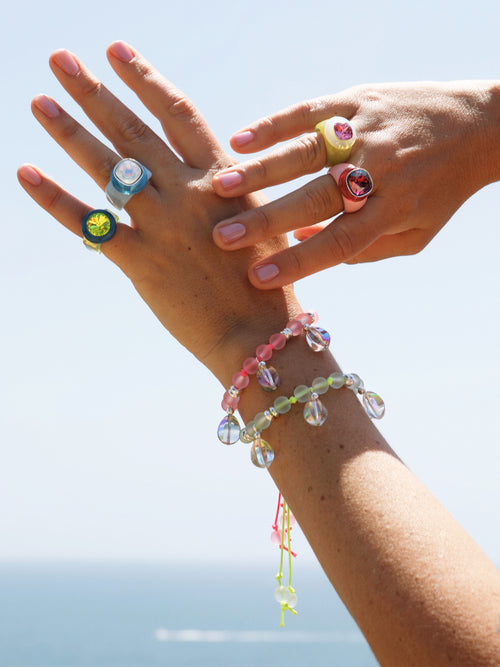 outdoor shot of MOUNSER Disco Pinky Ring in Pistachio featuring colorful acrylic resin and Swarovski crystal gemstone