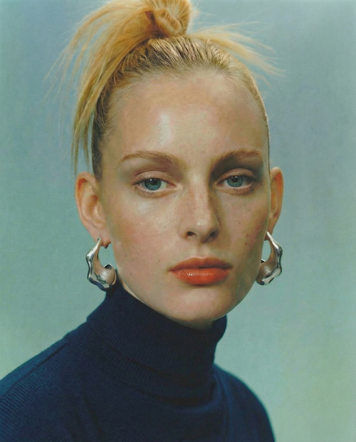 Close up of MOUNSER Large Rose Hoop Earrings in Sterling Silver, handcrafted sculptural free form earrings with a mirror polish on model