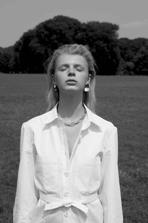 outdoor shot of MOUNSER Peel Earrings in Silver sxculptural statement wave shaped earring