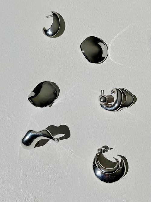 still life shot of MOUNSER Peel Earrings in Silver sculptural statement wave shaped earring