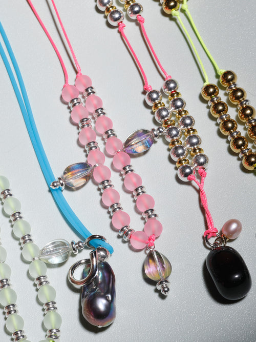 Still life of MOUNSER Seaside Souvenir Necklaces including the Agean a selection of colorful freshwater pearl beaded pendant necklaces 