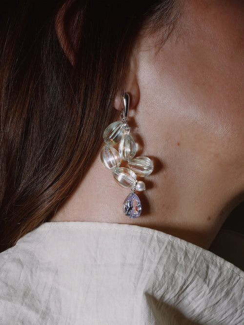 Model shot of MOUNSER Soap Earrings in Glow White sculptural glass asymmetric statement earrings.