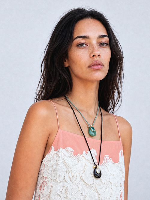 Model wearing MOUNSER Nereid Necklace in Lava colorway with obsidian pendant and gold-plated brass crystal setting on twisted silk cord.