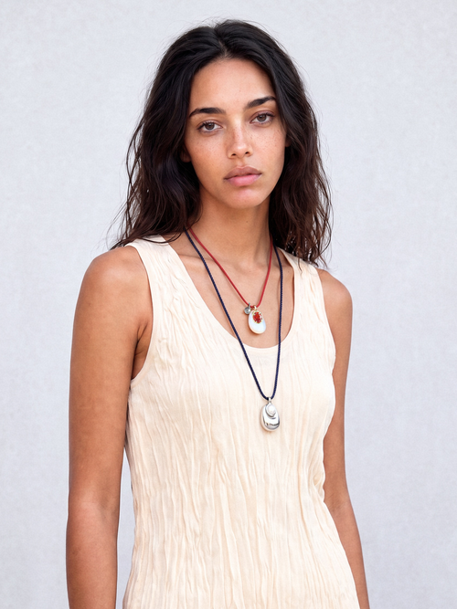 Model wearing MOUNSER Tide Pool Necklace with sculptural silver-plated brass freshwater pearl pendant on crimson twisted silk cord, styled with a dark ribbed sleeveless top.
