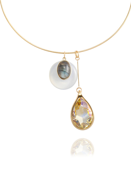 Close-up detail of the MOUNSER Rega Collar Necklace in Champagne showing the white quartz and labradorite dome pendant above an elongated Austrian crystal teardrop in 14k gold-plated brass setting, with reflection.