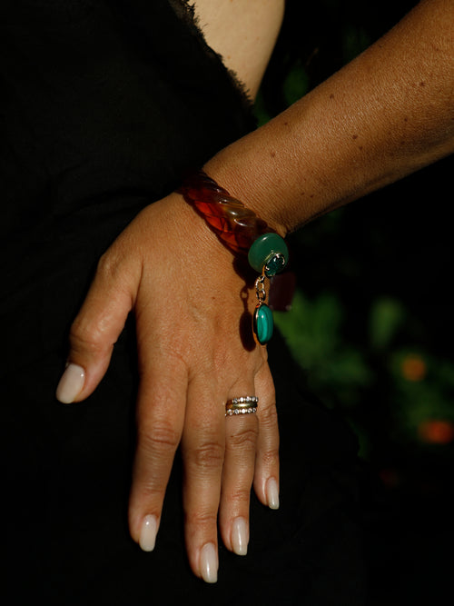 lose-up of the Scallop Drop Cuff in Tortoise Shell on the wrist, showing the tapered scallop-shell silhouette in amber brown resin with 14k gold and rhodium-plated brass details