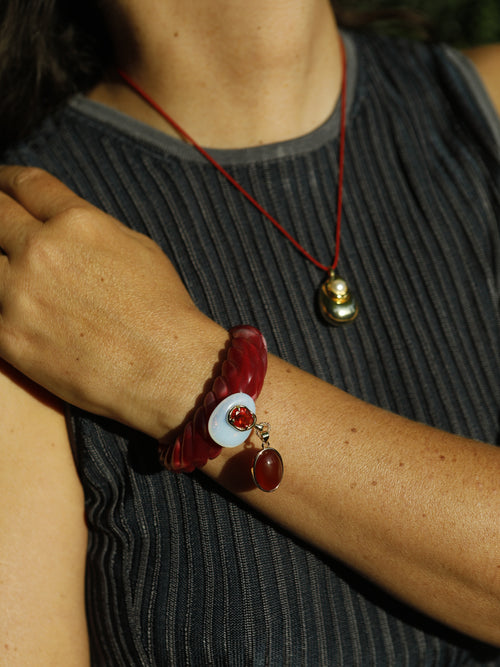 MOUNSER Scallop Drop Cuff in Urchin Red worn as a stacked statement bracelet, featuring an oxblood red sculptural resin silhouette with amethyst drop