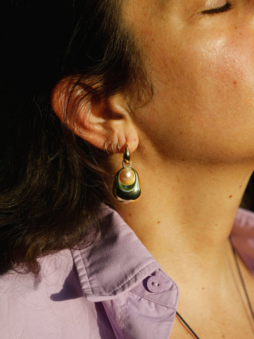 Woman wearing MOUNSER Tide Pool Earrings, sculptural gold freshwater pearl drop earrings on a huggie hoop, from the Seascape Abstracted Collection