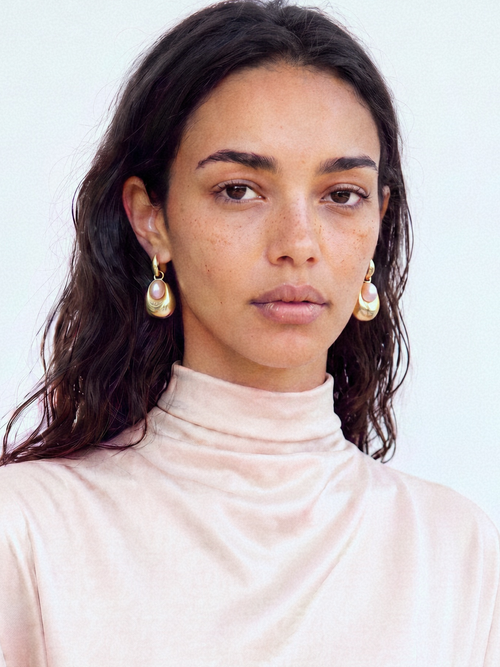 Woman wearing MOUNSER Tide Pool Earrings, sculptural gold freshwater pearl drop earrings on a huggie hoop, from the Seascape Abstracted Collection