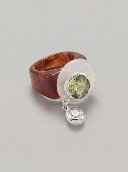 MOUNSER Caspian Ring in Shoreline - caramel brown acrylic resin ring with white quartz disc pale green Austrian crystal and cubic zirconia teardrop charm in rhodium-plated setting on neutral background