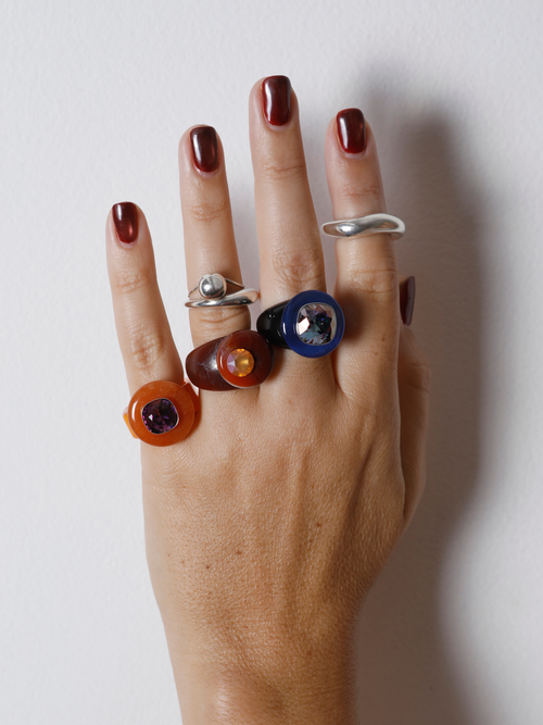 Close-up of the MOUNSER Orbital Ring in Terra on hand: carnelian disc pierced with a mini faceted orange crystal moon.