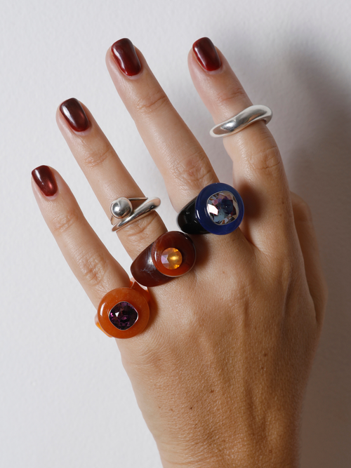 Close-up of the MOUNSER Ring Pop in Elderberry on hand: iridescent lavender Austrian crystal on a glossy blue and black resin band.