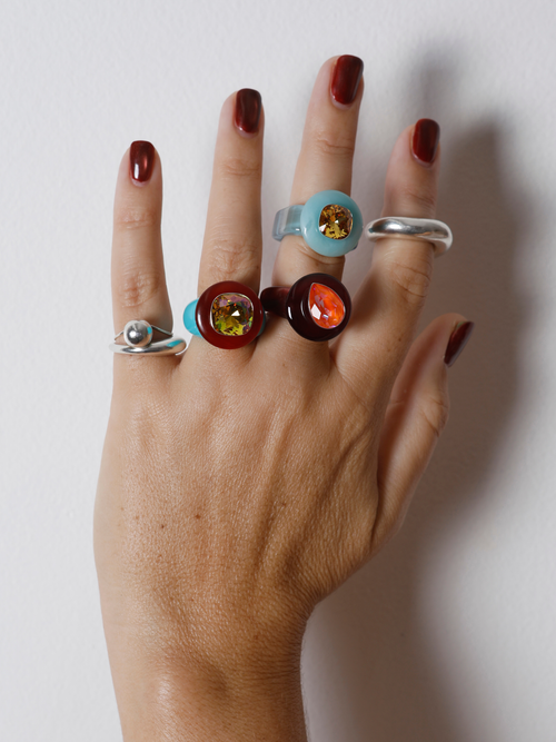 Close-up of the MOUNSER Ring Pop in Starfish on hand: iridescent yellow Austrian crystal on a glossy green resin band.
