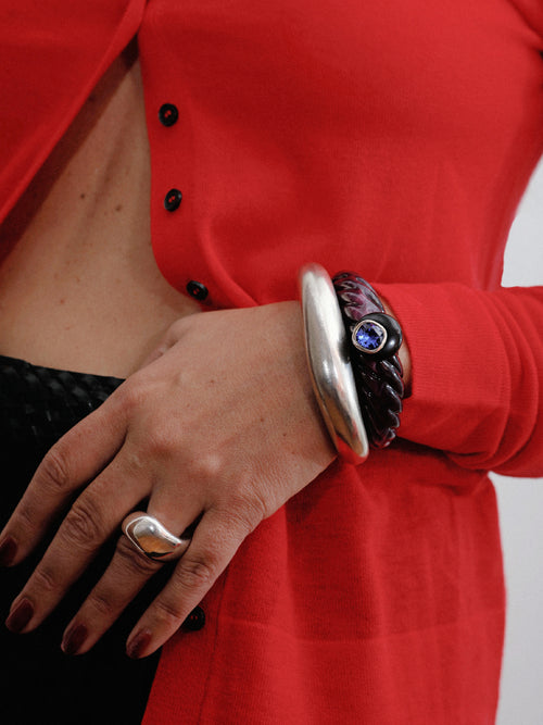Model wearing MOUNSER Scallop Cuff in Abyss - deep purple resin cuff with obsidian and sapphire crystal styled with sculptural silver ring and red shirt