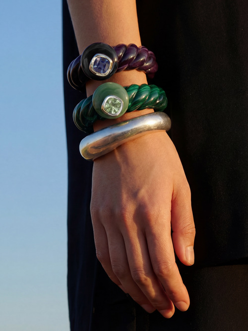 MOUNSER Scallop Cuff in Comber Green styled in cool tonal bracelet stack with Abyss cuff and silver MOUNSER cuff - deep green resin with jade crystal and purple resin with sapphire crystal against blue sky
