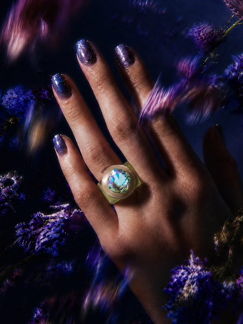 MOUNSER Spectrum Ring in Aloe worn on model's hand — milky light green limited edition cocktail ring with iridescent Austrian crystal on a dark purple floral background,  art object jewelry handcrafted to order in Los Angeles.