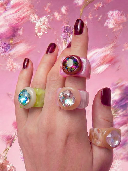 MOUNSER Spectrum Ring in Foundation worn on model's hand — milky beige limited edition cocktail ring with iridescent Austrian crystal on a pink floral background,  art object jewelry handcrafted to order in Los Angeles.