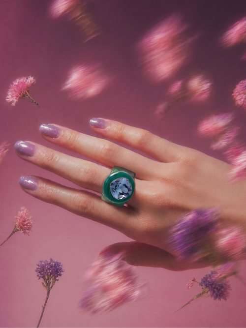 MOUNSER Spectrum Ring in Riviera worn on model's hand — milky green limited edition cocktail ring with iridescent Austrian crystal on a pink floral background,  art object jewelry handcrafted to order in Los Angeles.