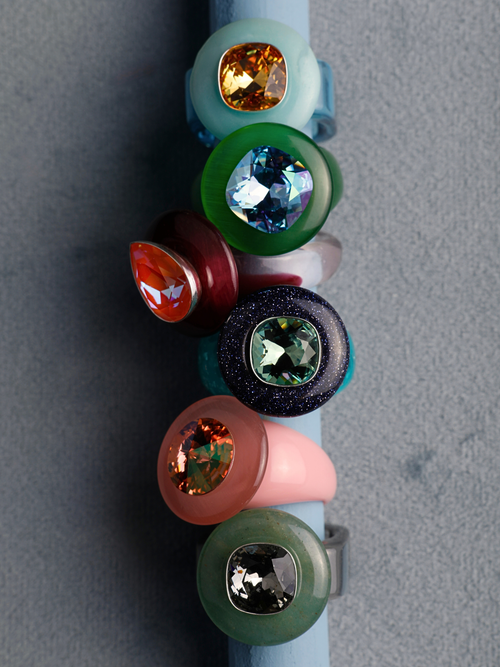  MOUNSER Tears of Joy Ring in King Crab, an orange and burgundy pear-shaped crystal ring in a still life styled in a ring stack.  handcrafted in LA.