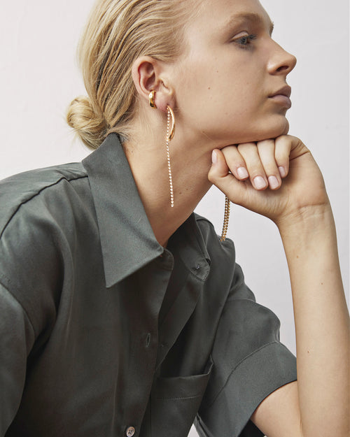model shot of MOUNSER Splash Earrings in Gold dangling  asymmetric earring style featuring crystal strands and angular hoops