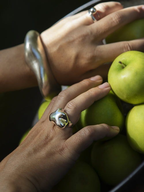 Outdoor photo of MOUNSER Storm Ring in sterling silver worn on hand showing organic sculptural shape and mirror finish